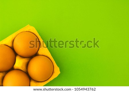 Fresh chicken eggs in a box on a green background