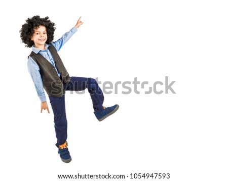 Image of an excited emotional boy preschooler in afro wig jumping isolated over white background wall pointing to copyspace.