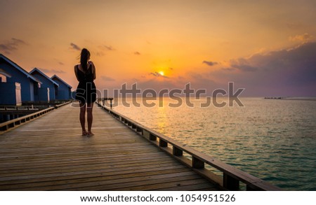 Silhouette of a girl taking a photo of amazing sunset in Maldives