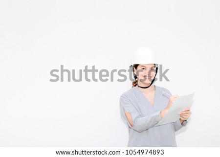 woman engineer wears Safety Helmet holding drawing paper. Stand on the right of the picture with old white wall background