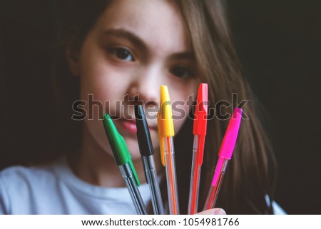smiling cute girl with colored handles in fan shape on black background.
