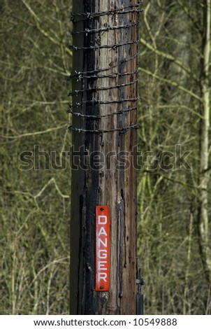 Danger sign and barbed wire on a telegraph pole