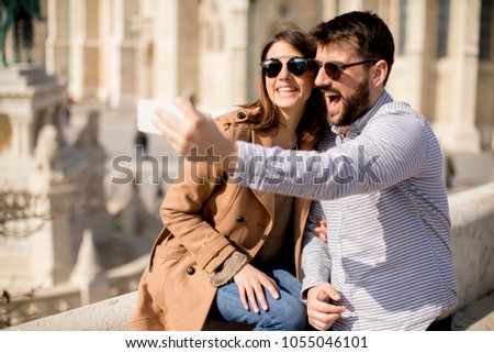 Portrait of loving couple taking selfie in urban environment at sunny day