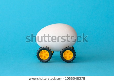 White Easter egg on wheels on a blue background