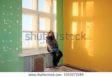 Lonely kid girl in abandoned old children school, oldish walls with creacked painter yellow blue green walls, forsaken strange left our deserted scenery, film look, athmosperic light of empty rooms