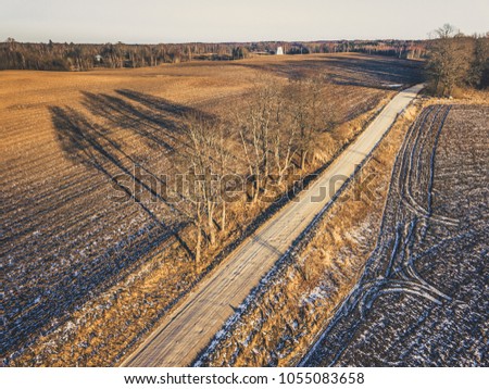Aerial Drone Photography of a Countryside Road in Sunny Winter Day with a Little Snow on the Sides an Trees in the Background - vintage look edit