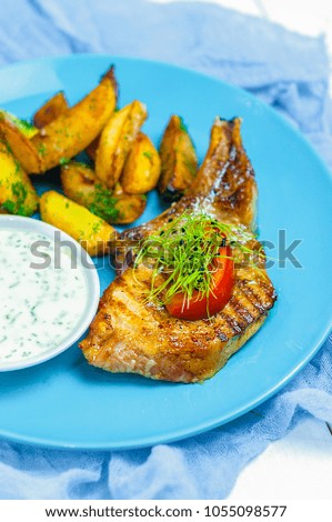 Grilled beef pork steak minion with creamy sauce and potatoes on blue plate. Meat food closeup
