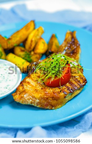 Grilled beef pork steak minion with creamy sauce and potatoes on blue plate. Meat food closeup