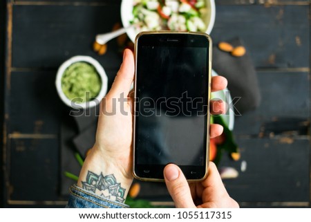 Woman hands takes photography of food on table with phone. Dinner or lunch. Empty screen. Smartphone photo for social networks post. Vegetarian, healthy, organic 