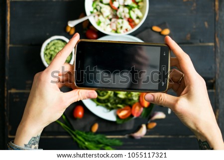 Woman hands takes photography of food on table with phone. Dinner or lunch. Empty screen. Smartphone photo for social networks post. Vegetarian, healthy, organic 