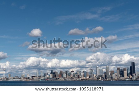 The Seattle skyline viewed from West Seattle under blue partly cloudy skies, circa March 2018 wide landscape.