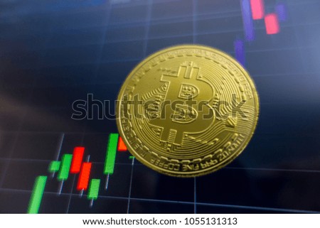 Golden Bitcoin on black laptop screen with stock exchange graph background. Digital money concept. 