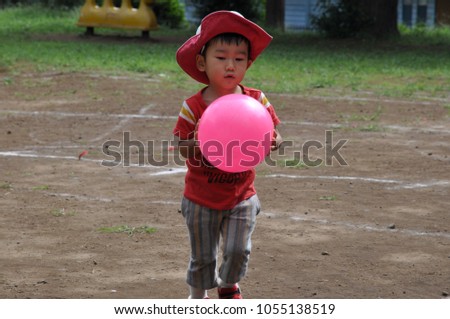 asian boy play with pink ball at park 