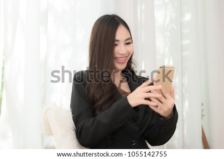 Businesswoman wearing a black suit. Sitting in the room happily.Asian girl wearing black suit is working at notebook computer. -Business Concept