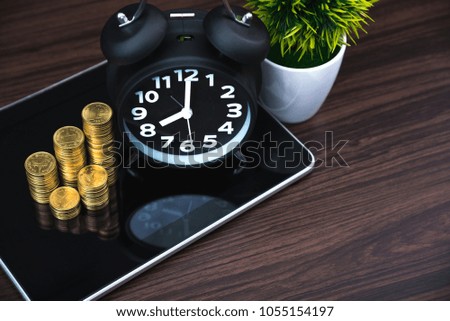 Coins stacks and alarm clock with tablet computer and financial graph, business planning vision and finance analysis concept idea.