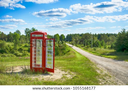 Old  red british telephone booth in the field