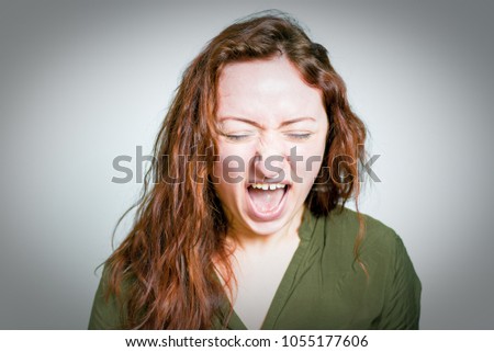 Pretty red-haired girl rejoices victory funny, isolated on a gray background