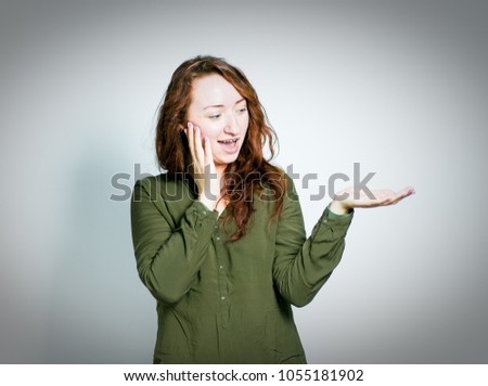 lovely red-haired girl shows your product or text on the palm of your hand, isolated on a gray background