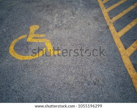 Yellow signs show parking for the disabled on the outdoor asphalt parking lot.physically challenged.