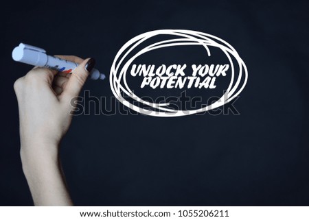 The businessman writes an inscription with a white marker:UNLOCK YOUR POTENTIAL