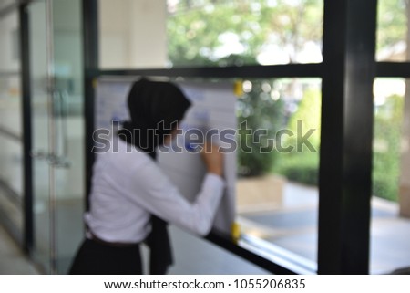 Blur image, A girl is writing on white paper.