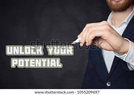 The businessman writes an inscription with a white marker:UNLOCK YOUR POTENTIAL
