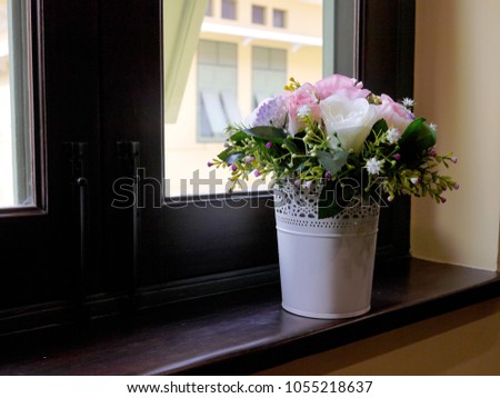 Vase of roses is placed by the window
