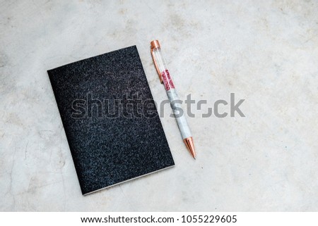Glam black glitter notepad with rose gold pen on gray concrete background. Copy space for text. Minimalism fashion, beauty blogging, freelancing concept. 