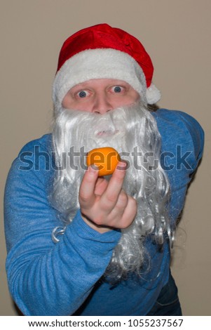 Santa Claus and Mondarin in their hands. Santa Claus looks at tangerine