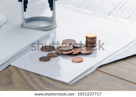 private business: pile of copper coins in front of the background stamp and contracts on the table, short focus, close