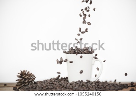 The coffee beans fall on glass is placed on the table on a white background