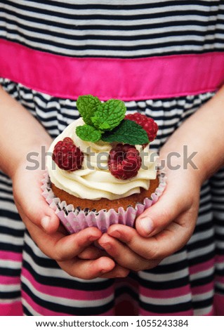 Little girl holding birthday cupcake with raspberries