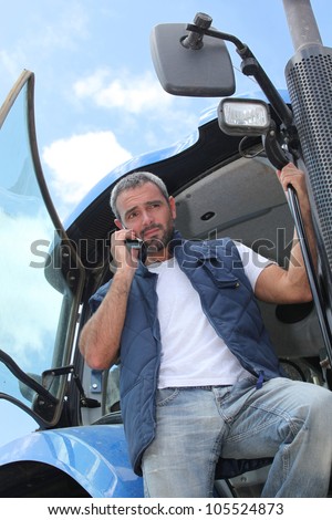 Farmer getting down from tractor with mobile phone