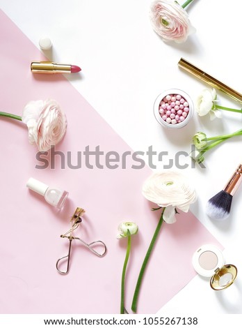 Makeup cosmetic products and pink ranunculus flowers flat lay, top view on white pink background. Pearl make up powder and brush, lipstick, accessories. Copy space
