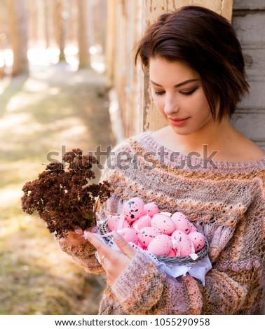 Spring garden and the woman with a basket of pink eggs