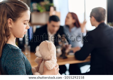 Young couple arranges guardianship of little girl. Registration of guardianship. Family in office of family lawyer. Two parents fighting over child in divorce concept. Royalty-Free Stock Photo #1055292158