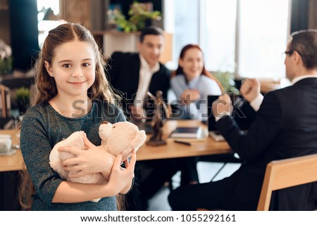Happy little girl is hugging teddy bear at office of family lawyer. Registration of guardianship. Family in office of family lawyer. Royalty-Free Stock Photo #1055292161
