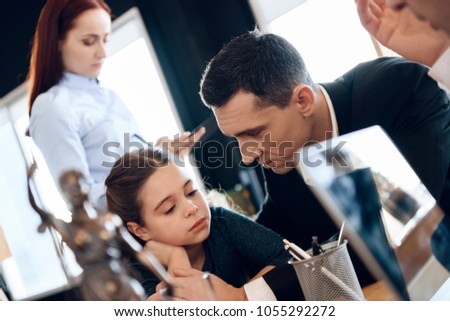 Adult father calms daughter while sitting at desk in office of family lawyer. Registration of guardianship of little girl.