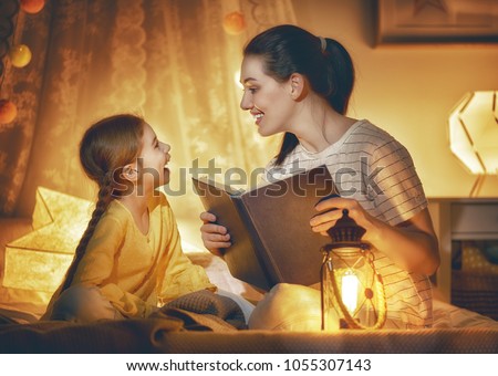 Family time. Pretty young mother reading a book to her daughter. Happy time at home. Royalty-Free Stock Photo #1055307143
