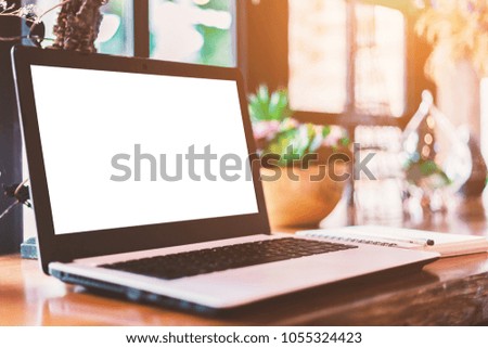 Mockup image of laptop with blank white screen on wooden table of In the coffee shop.