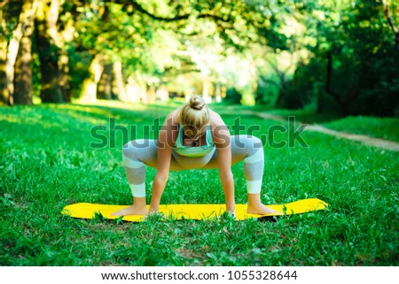 Young pregnant girl doing yoga in the park