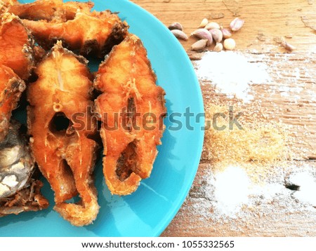 Tilapia fried on blue plate and have sugar,corn powder,pepper on wooden background