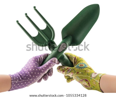 Crossed garden tools in gloved hands isolated on white background