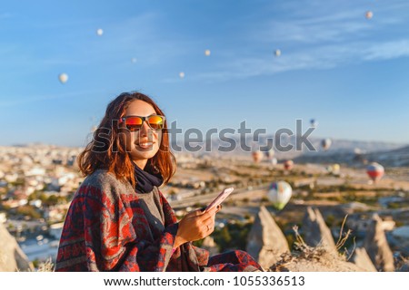 A tourist girl talks by the phone of the hills in Cappadocia in Turkey. Travel, tourism, hiking, vacation.