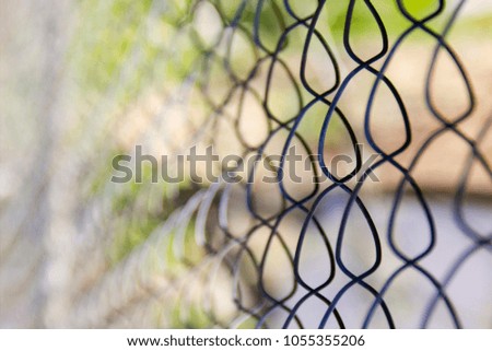 Wire metal mesh (fence) on a background of green grass, texture, background, building material. An image for connecting to a network or a restricted area or security zone. Close-up, selective focus.