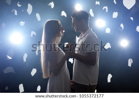 Young loving couple dancing against dark background with backlit
