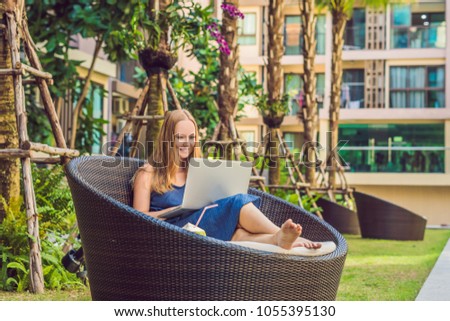 Young female freelancer sitting near the pool with her laptop in the hotel browsing in her smartphone. Busy at holidays. Distant work concept. Copy space for your text
