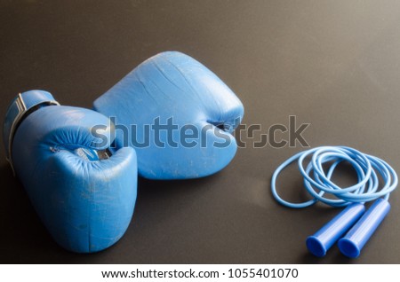 Blue old boxing gloves and blue skipping rope on a gray background