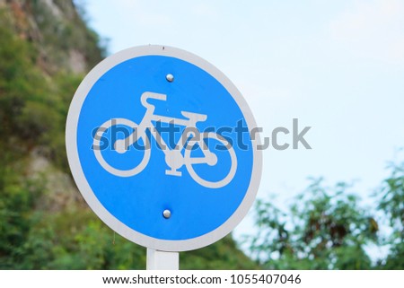 bicycle zone sign, blue and white circle symbol, sky and mountain background 