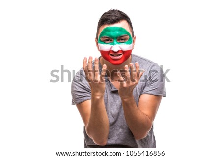 Handsome man supporter fan of Iran national team painted flag face get unhappy sad frustrated emoitions into a camera.